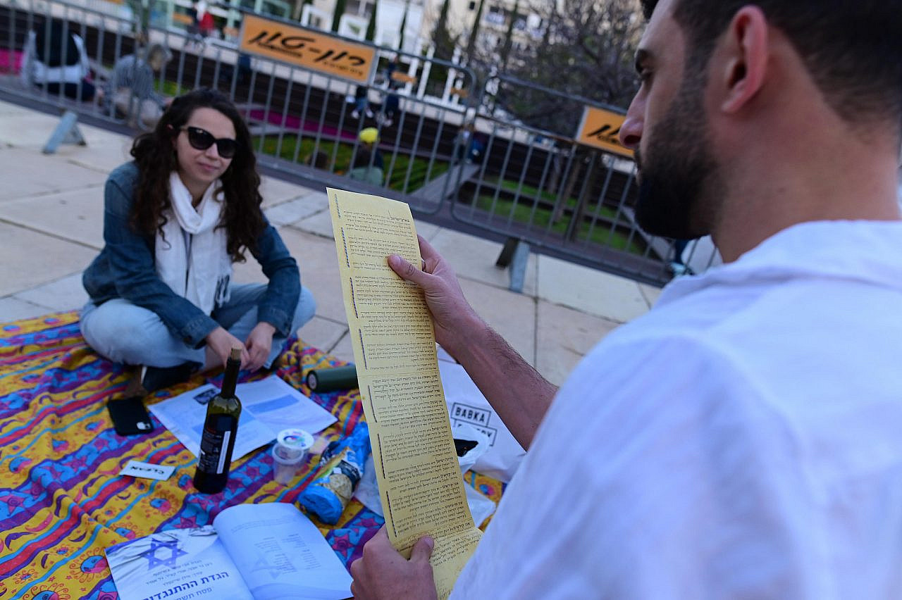 Israelis read a copy of Israel's Declaration of Independence at a Passover picnic protest against the Israeli government's planned judicial overhaul, at HaBima square in Tel Aviv, April 6, 2023. (Tomer Neuberg/Flash90)
