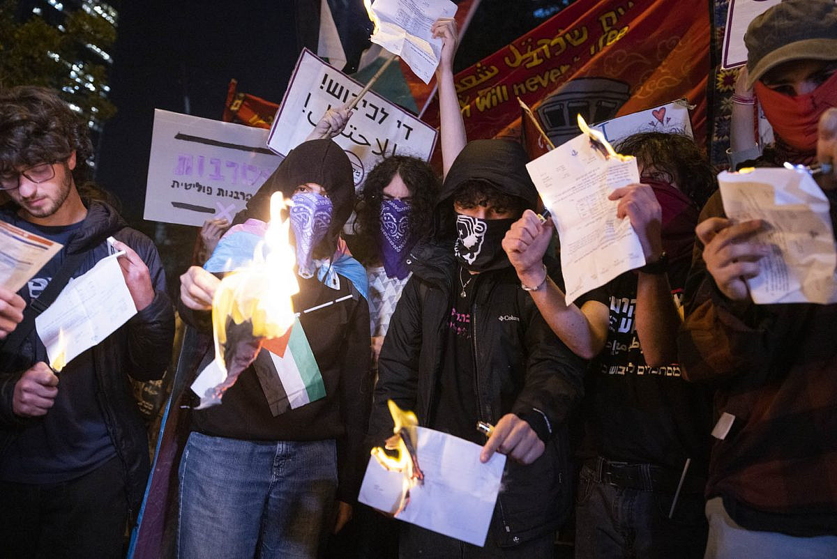 Young protesters burn their draft orders for the Israeli army during a protest against the government in Tel Aviv, April 1, 2023. (Oren Ziv)