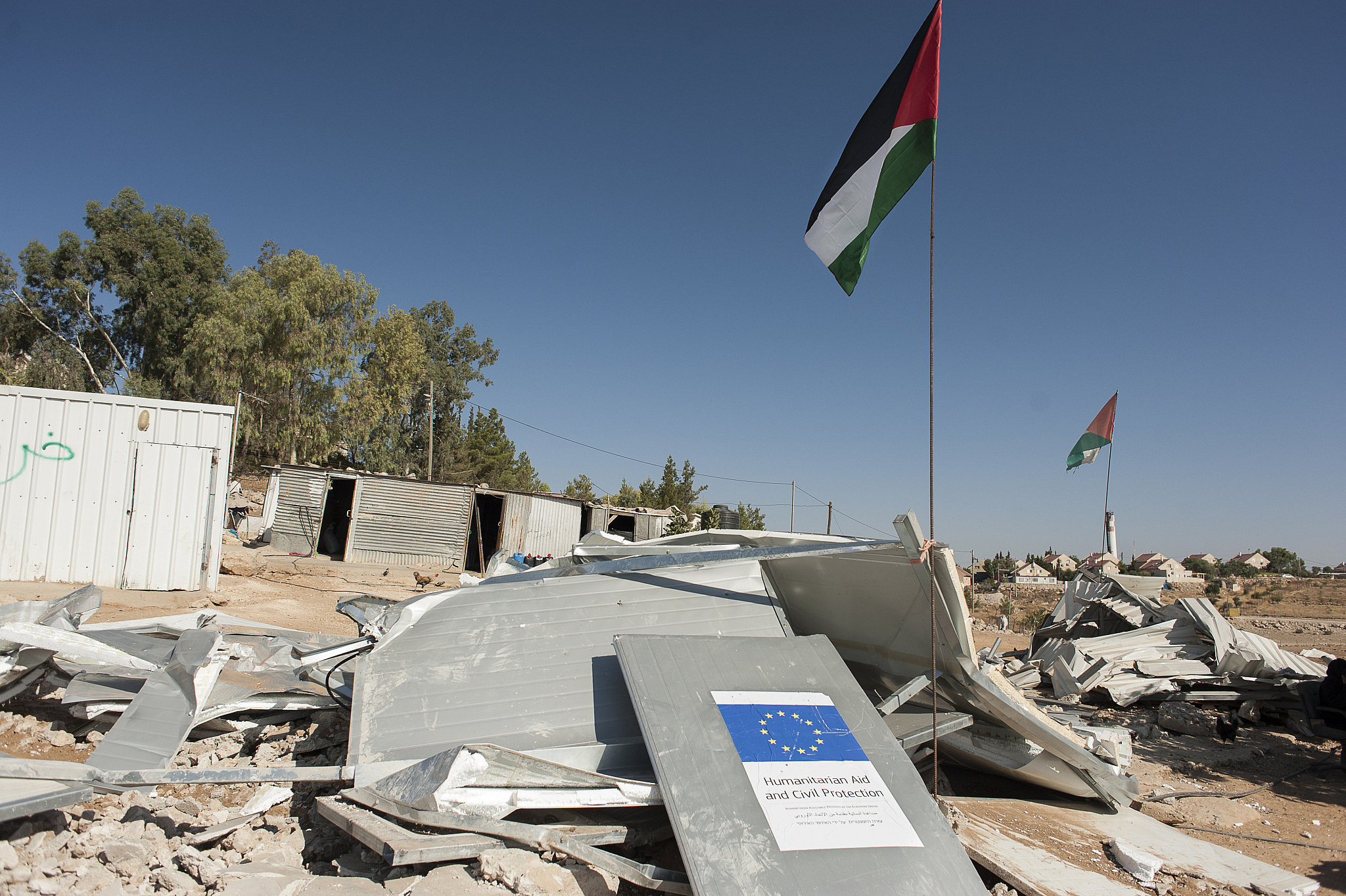 A sign bearing the name of the European Union is seen in the ruins of a house that was demolished by Israeli forces, Umm al Khair, South Hebron, West Bank, August 9, 2016. (Martin Barzilai/Activestills)
