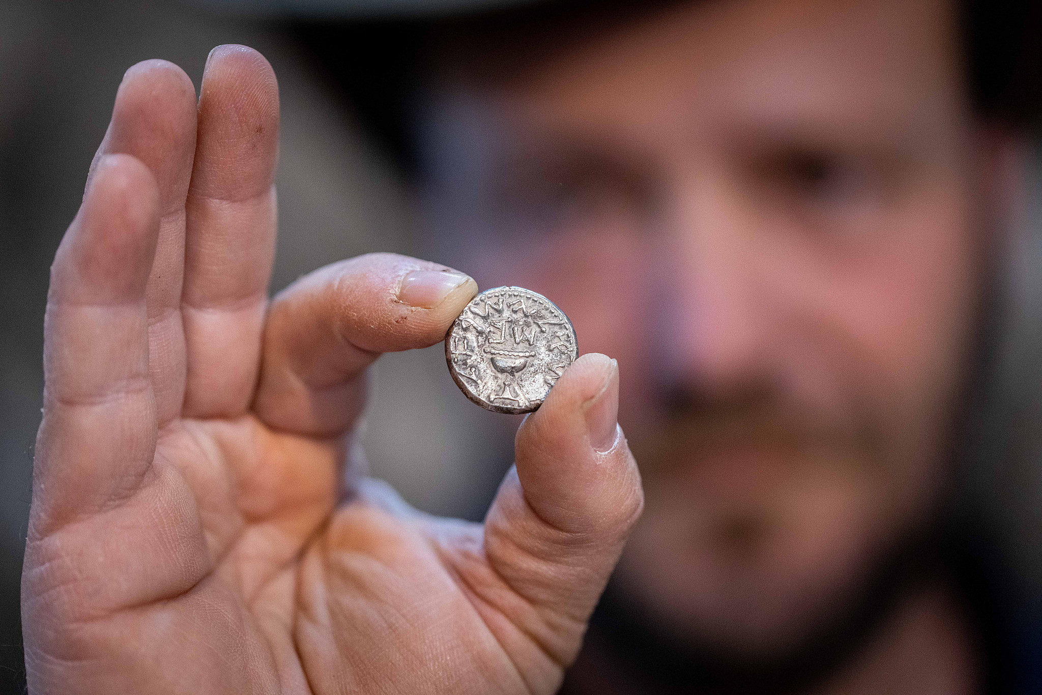 Archaeologist of the Israel Antiquities Authority (IAA) Ari Levi holds a rare 2,000-year-old silver coin at the Pilgrimage Road at the City of David, in the East Jerusalem neighborhood of Silwan, November 23, 2021. (Yonatan Sindel/Flash90)