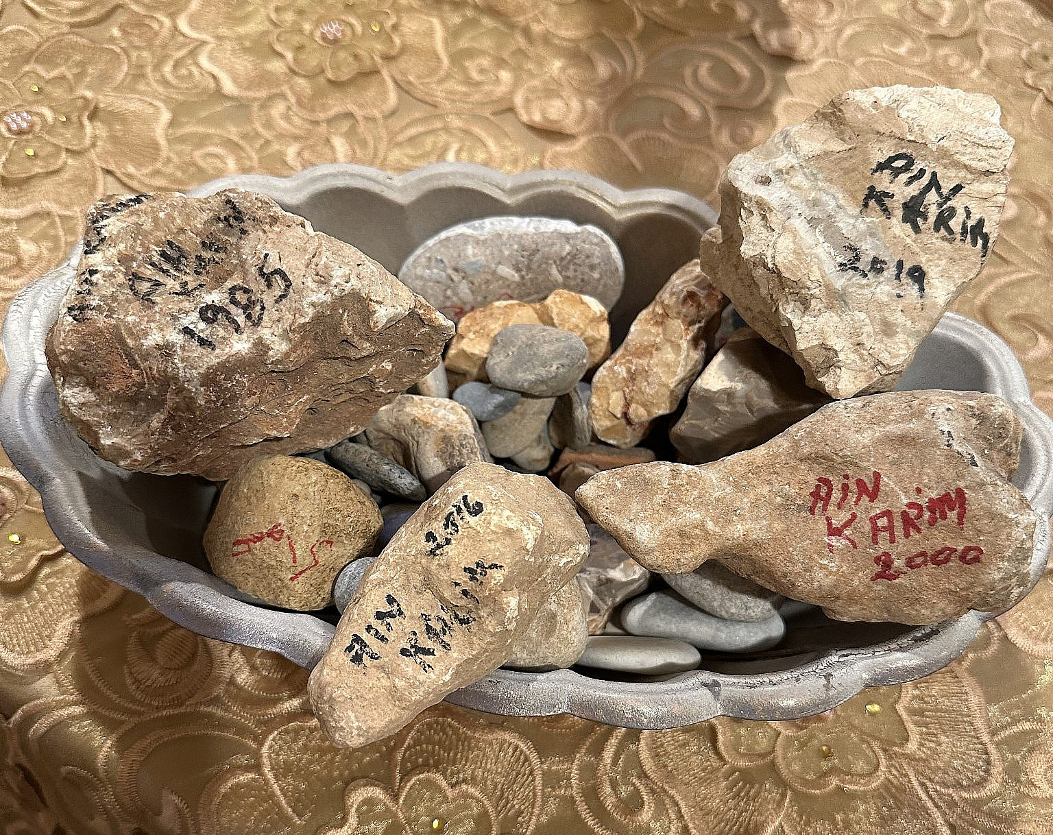 Stones collected by Leila Giries from her uprooted village of Ain Karem, on which she wrote the name and years of her visits. (Courtesy)