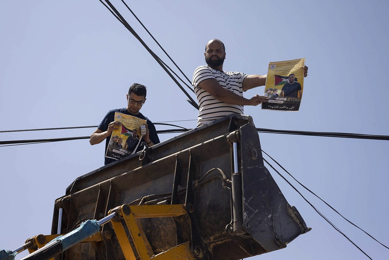 Residents of Turmus Ayya in the occupied West Bank hold up a photo of Omar Qattin, 27, who was shot dead by Israeli police following a settler attack on the town, June 22, 2023. (Oren Ziv)