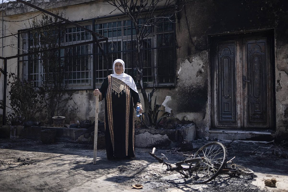 Khalija Diab, 75, stands outside her house in Turmus Ayya in the occupied West Bank, the day after settlers set it on fire, June 22, 2023. (Oren Ziv)