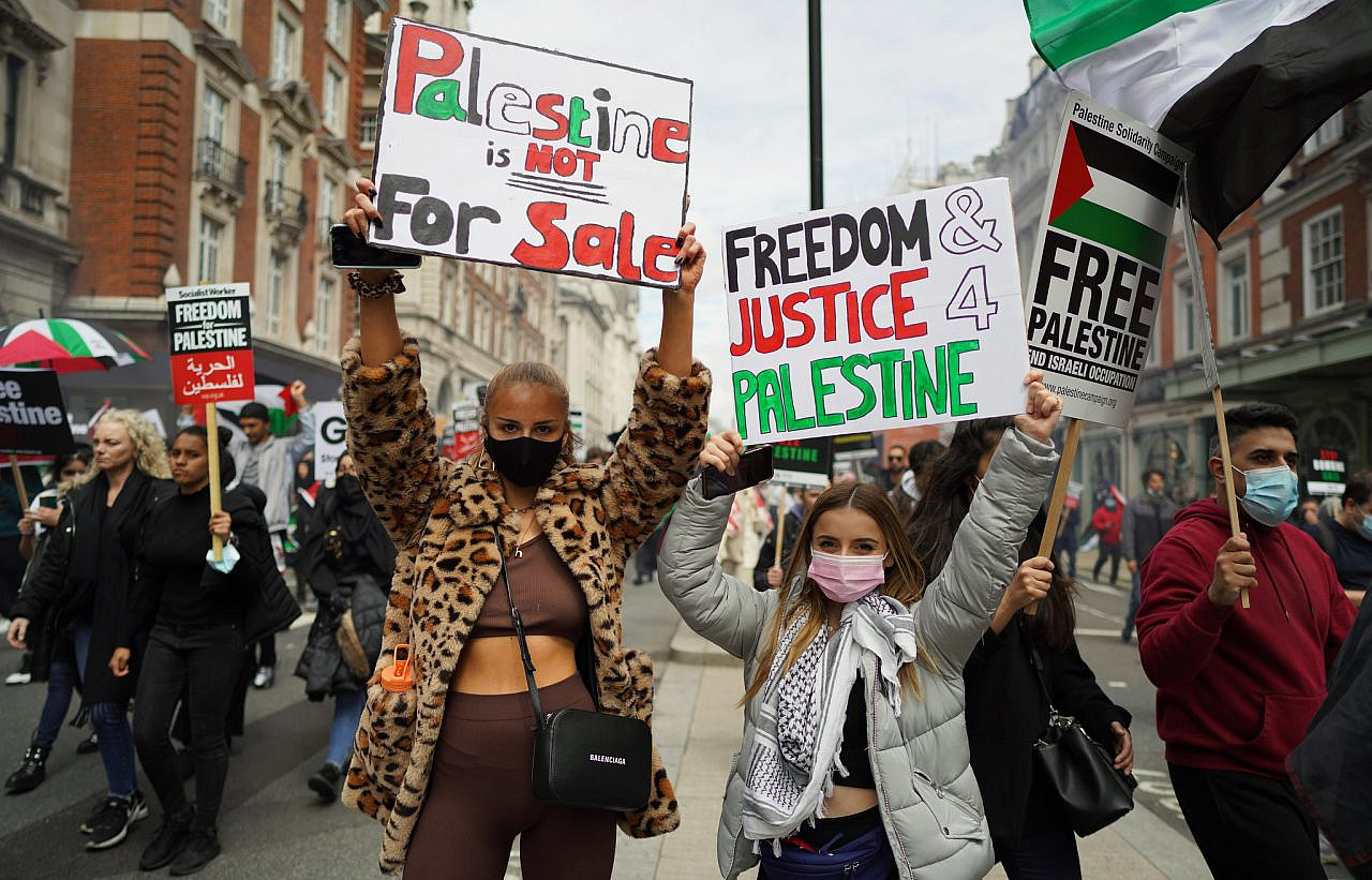 Protesters hold placards as tens of thousands march in solidarity with Palestine in London, UK, May 23, 2021. (Alisdare Hickson/CC BY-SA 2.0)