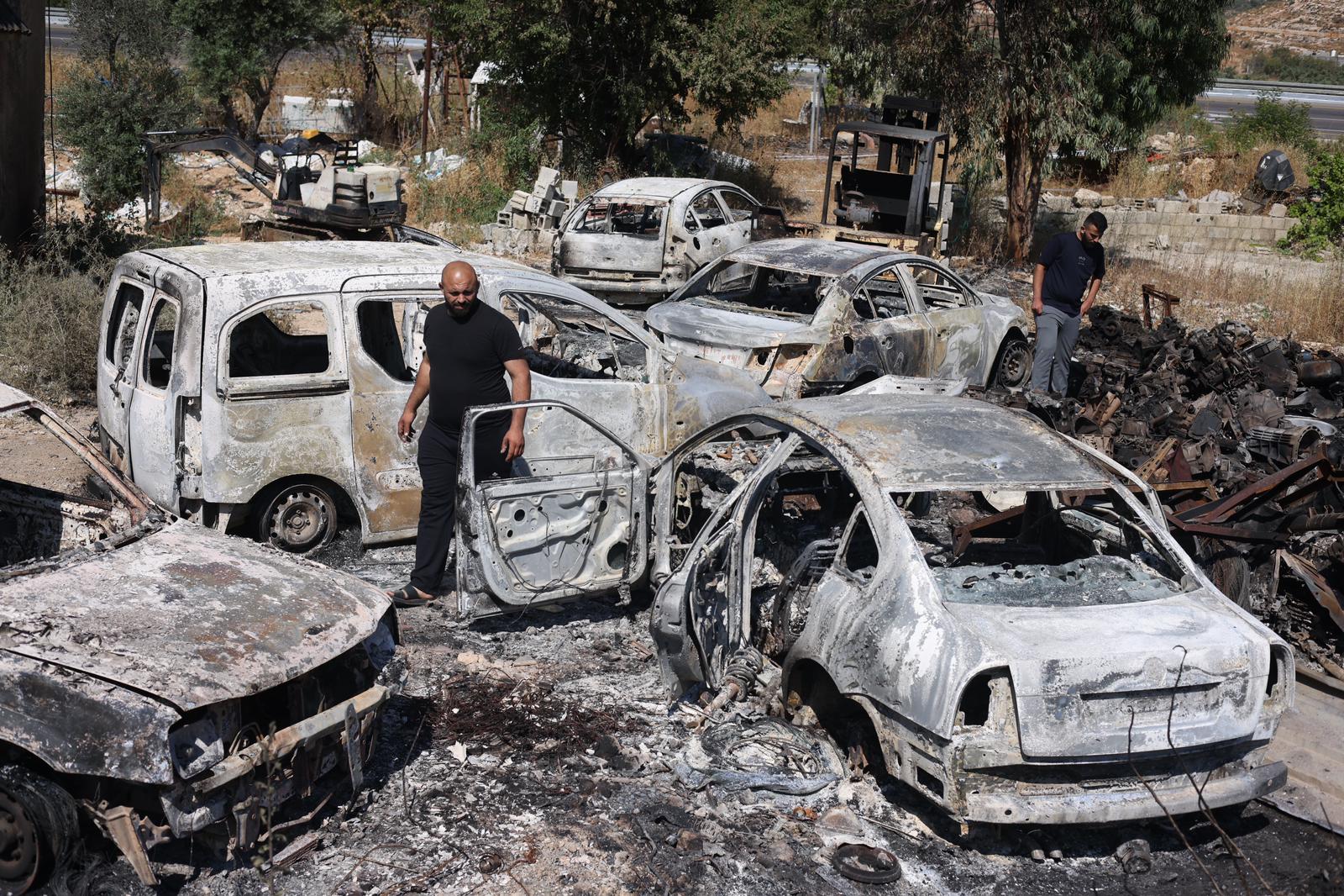 Palestinians asses the damage after settlers burned cars and damaged property in the West Bank village of Al-Lubban ash-Sharqiya, June 21, 2023. (Oren Ziv)