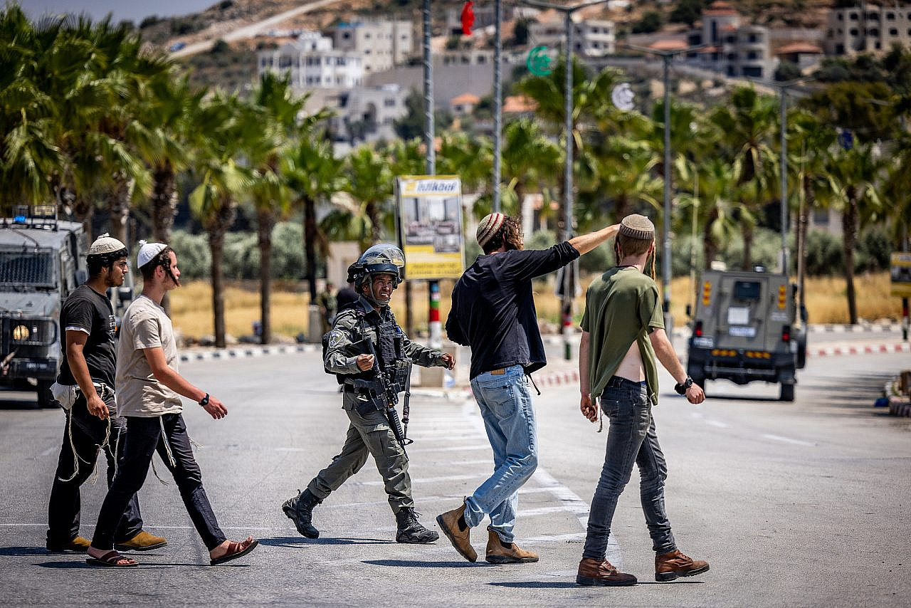 Israeli security forces argue with Jewish settlers at the entrance to the West Bank village of Turmus Ayya, June 21, 2023. (Yonatan Sindel/Flash90)