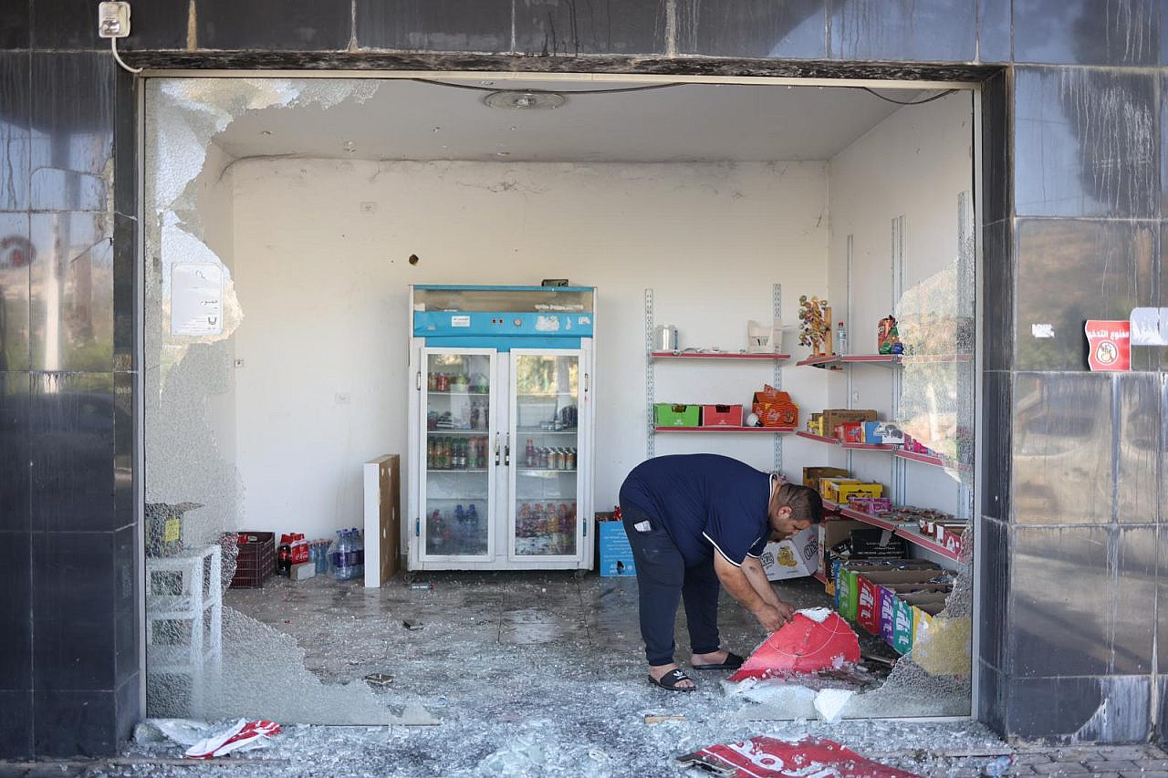 Palestinians asses the damage after settlers attacked businesses and burned cars in the West Bank village of Al-Lubban ash-Sharqiya, June 21, 2023. (Oren Ziv)