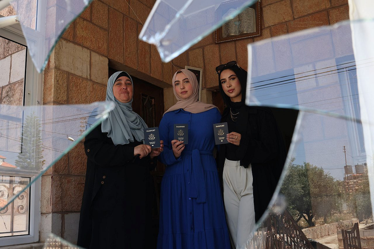 Olfat Abdel Aziz (left), with her daughters Nur (center) and Amal (right), photographed with their U.S. passports in their home that was damaged during a settler pogrom in Turmus Ayya, occupied West Bank. (Oren Ziv)