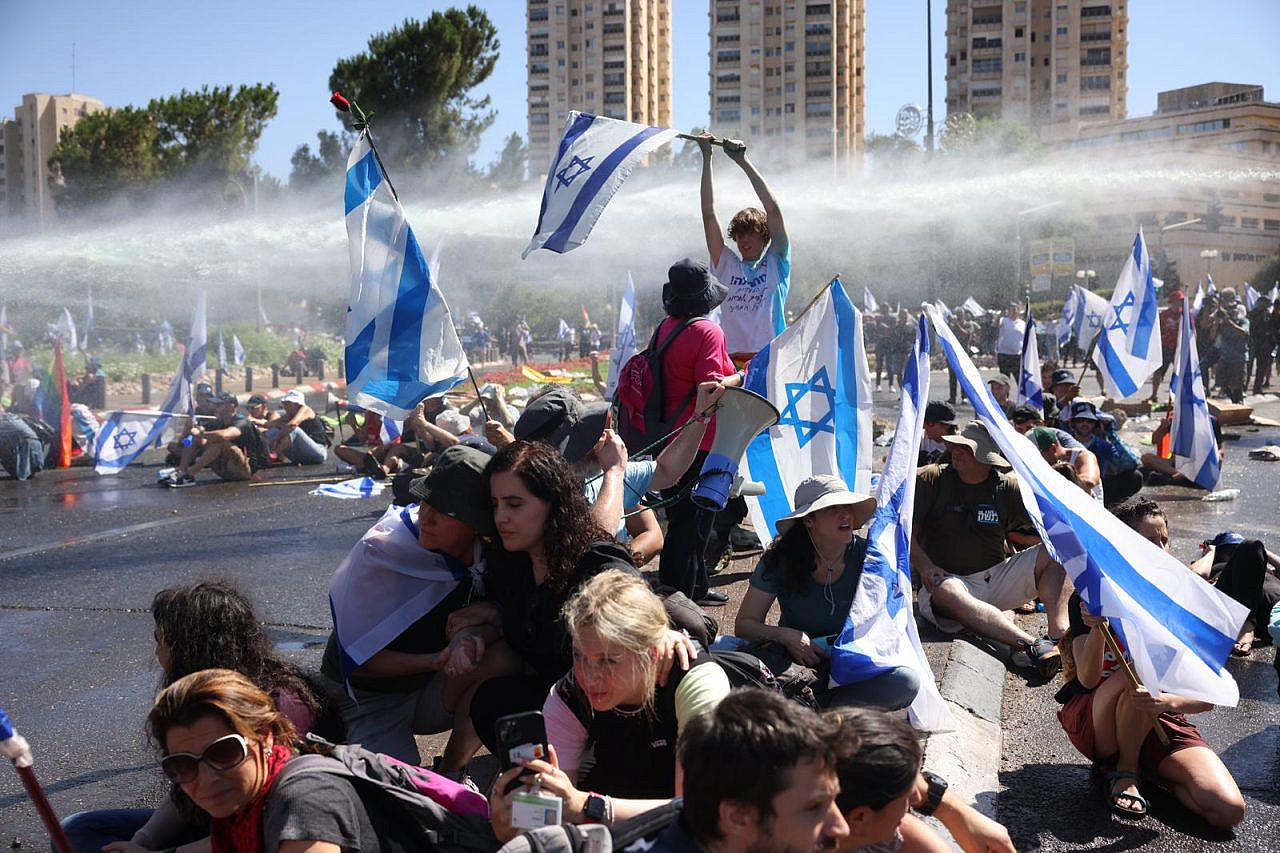 A water cannon sprays anti-government demonstrators, including MK Naama Lazimi, outside the Knesset, July 24, 2023. (Oren Ziv)