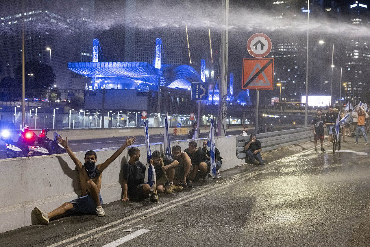 Israeli demonstrators take shelter during an anti-government protest, Tel Aviv, July 20, 2023. (Oren Ziv)