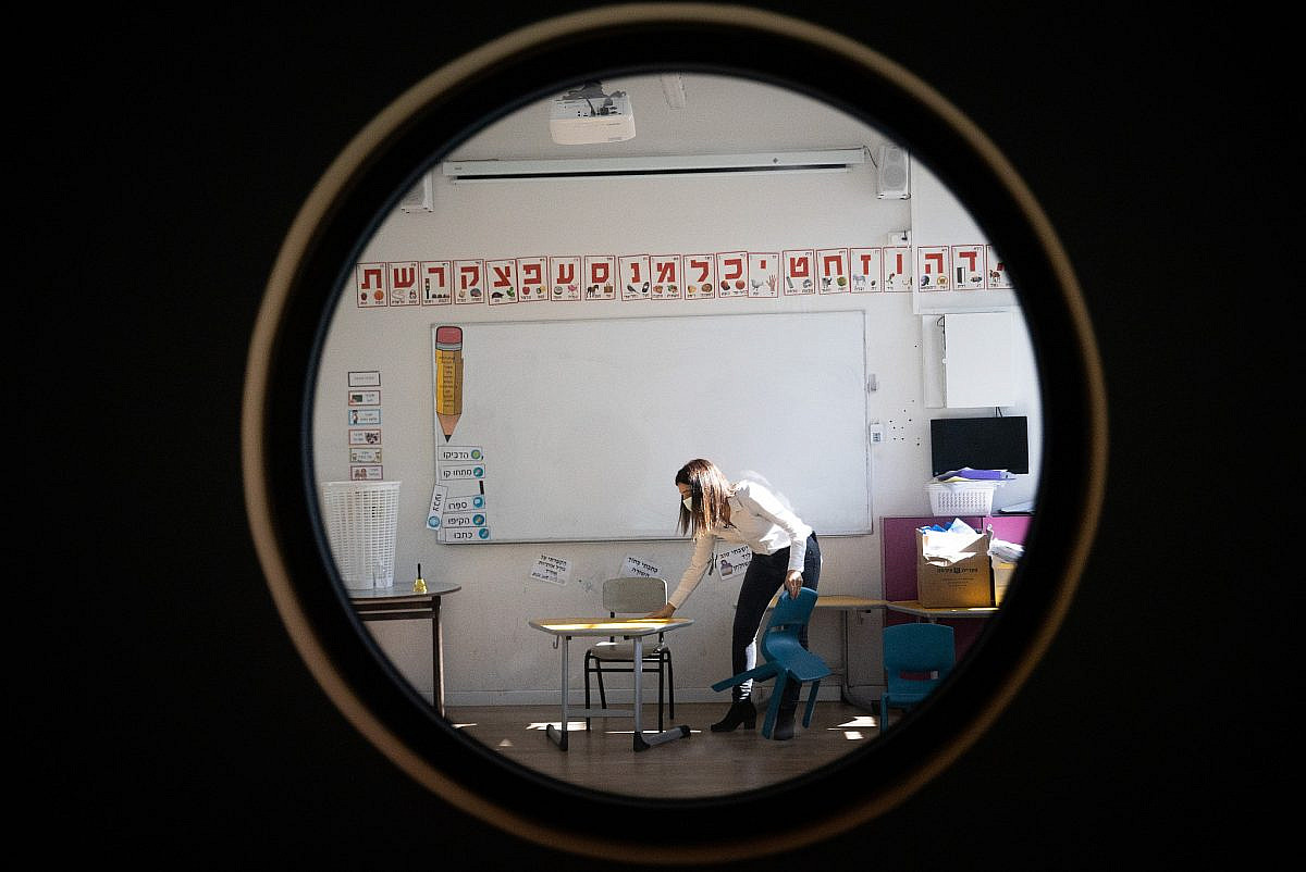 A high school principal arranges her classroom for the reopening of the school in Jerusalem, February 10 2021. (Yonatan Sindel/Flash90)