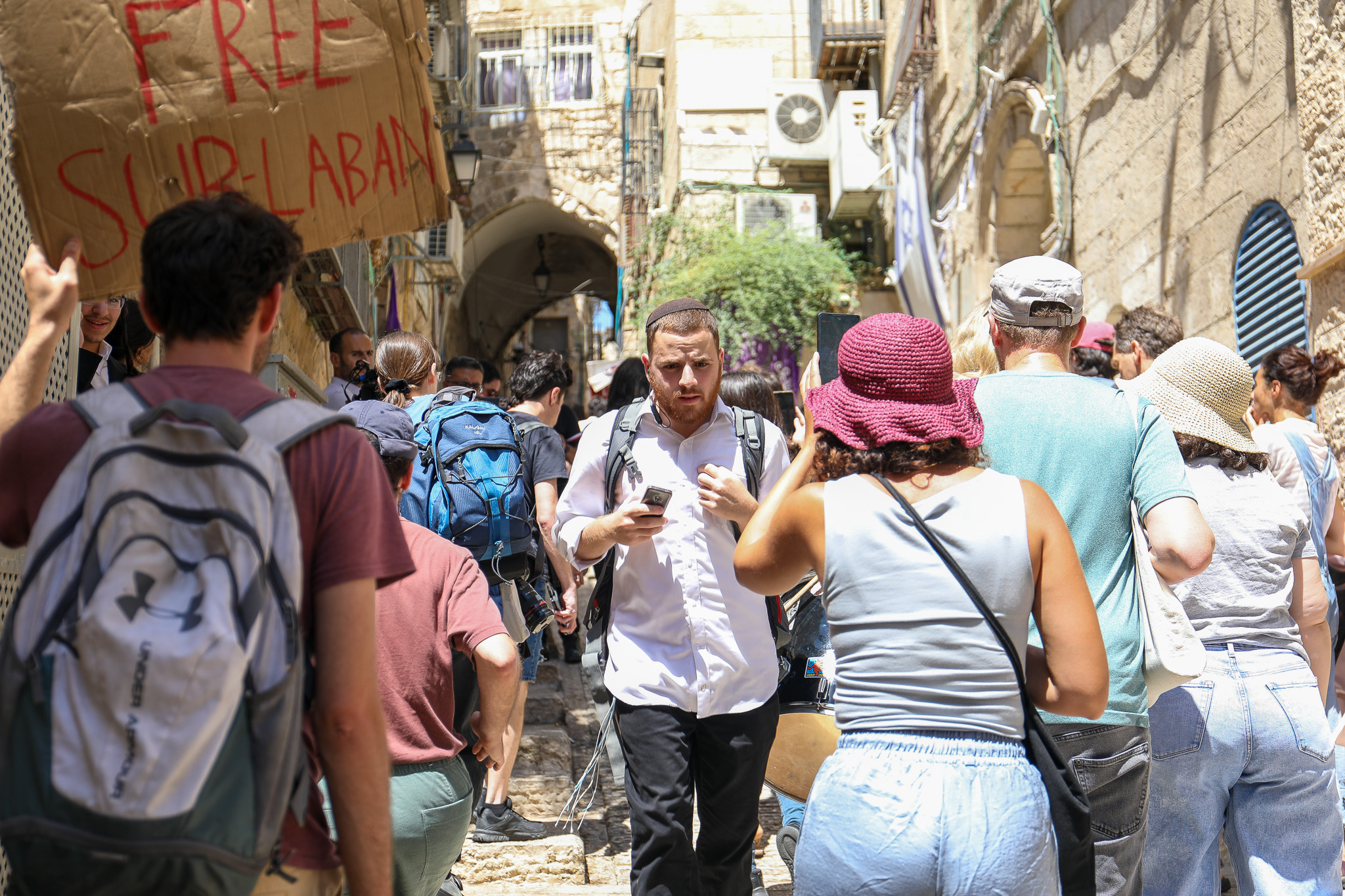 An Israeli settler walks through a group of activists protesting the expulsion of the Ghaith Sub-Laban family from their home in the Old City of Jerusalem, July 11, 2023. (Yahel Gazit)