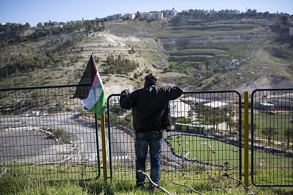 A Palestinian man looks over the Israeli settlement of Ma’ale Adumim during a protest-tent action against a bill that would annex the settlement bloc to Israel, Al 'Ezariya, West Bank, January 20, 2017. (Anne Paq/Activestills)