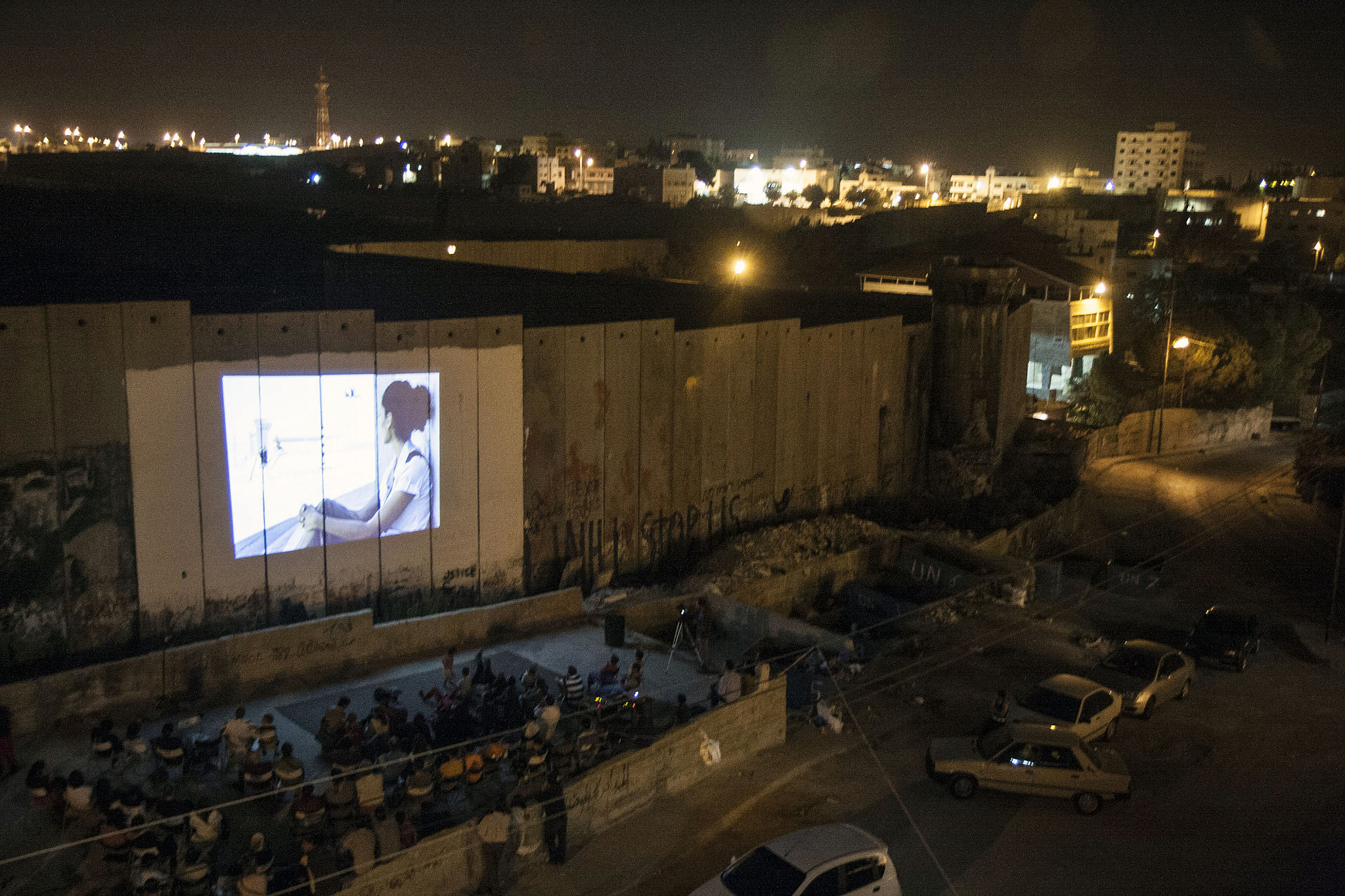 Palestinians watch a film screened on the Israeli Separation Wall as part of a festival, Aida refugee camp, August 29, 2008. (Anne Paq/Activestills)