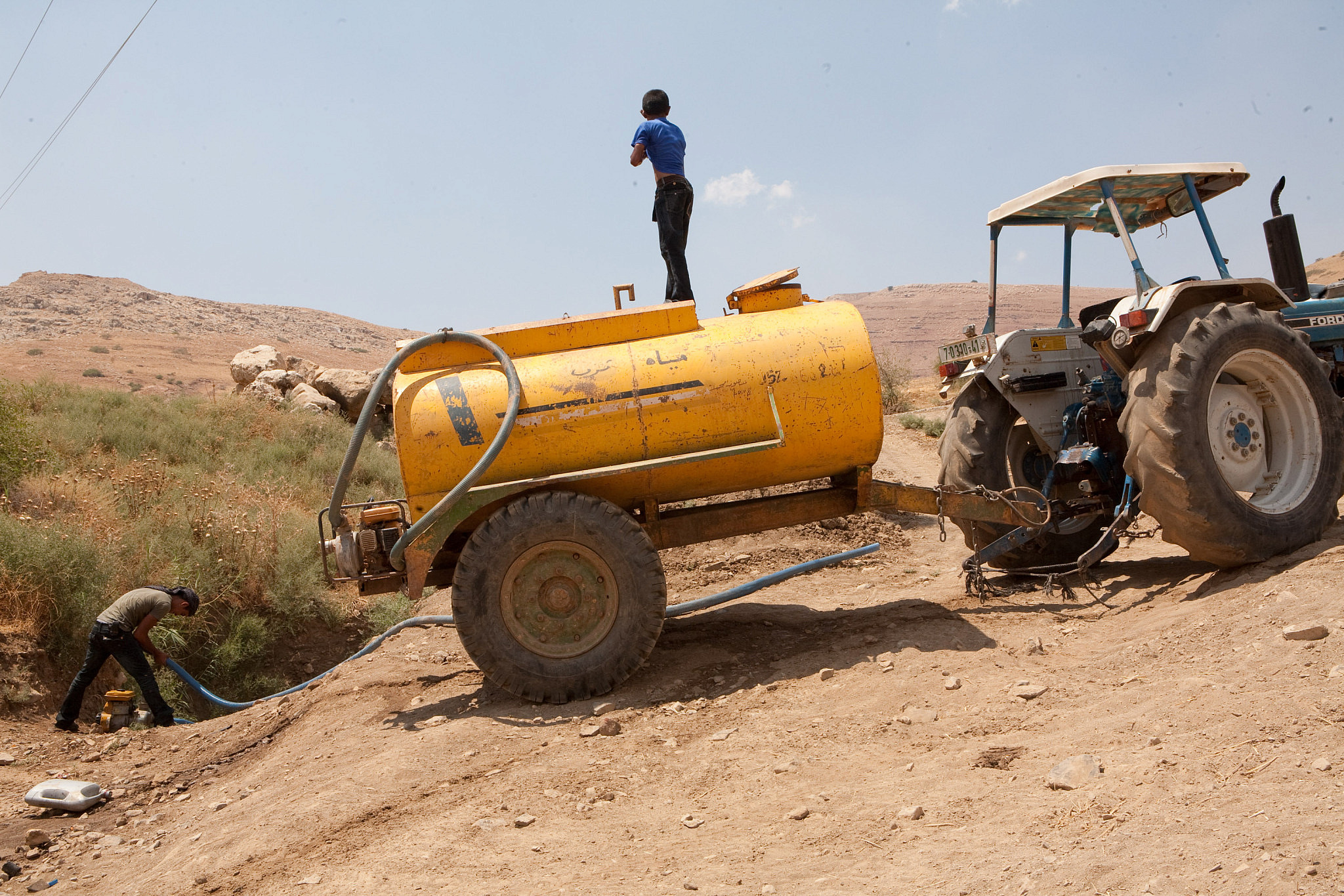 Palestinians pumping water from a natural spring, Jordan Valley, West Bank, July 23, 2009. (Keren Manor/Activestills)