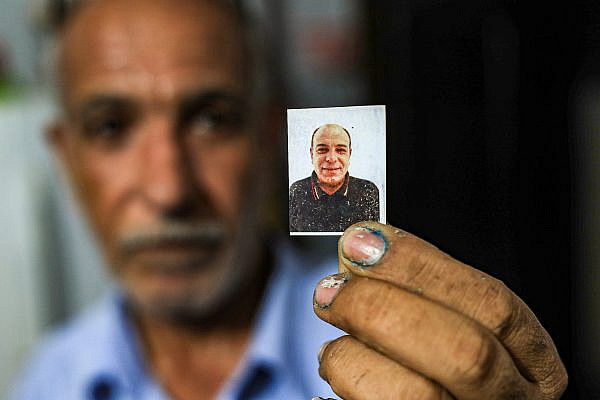 Riad al-Gul holds a photo of his brother, Ziad, who died in a workplace accident in Israel. (Mohammed Zaanoun)