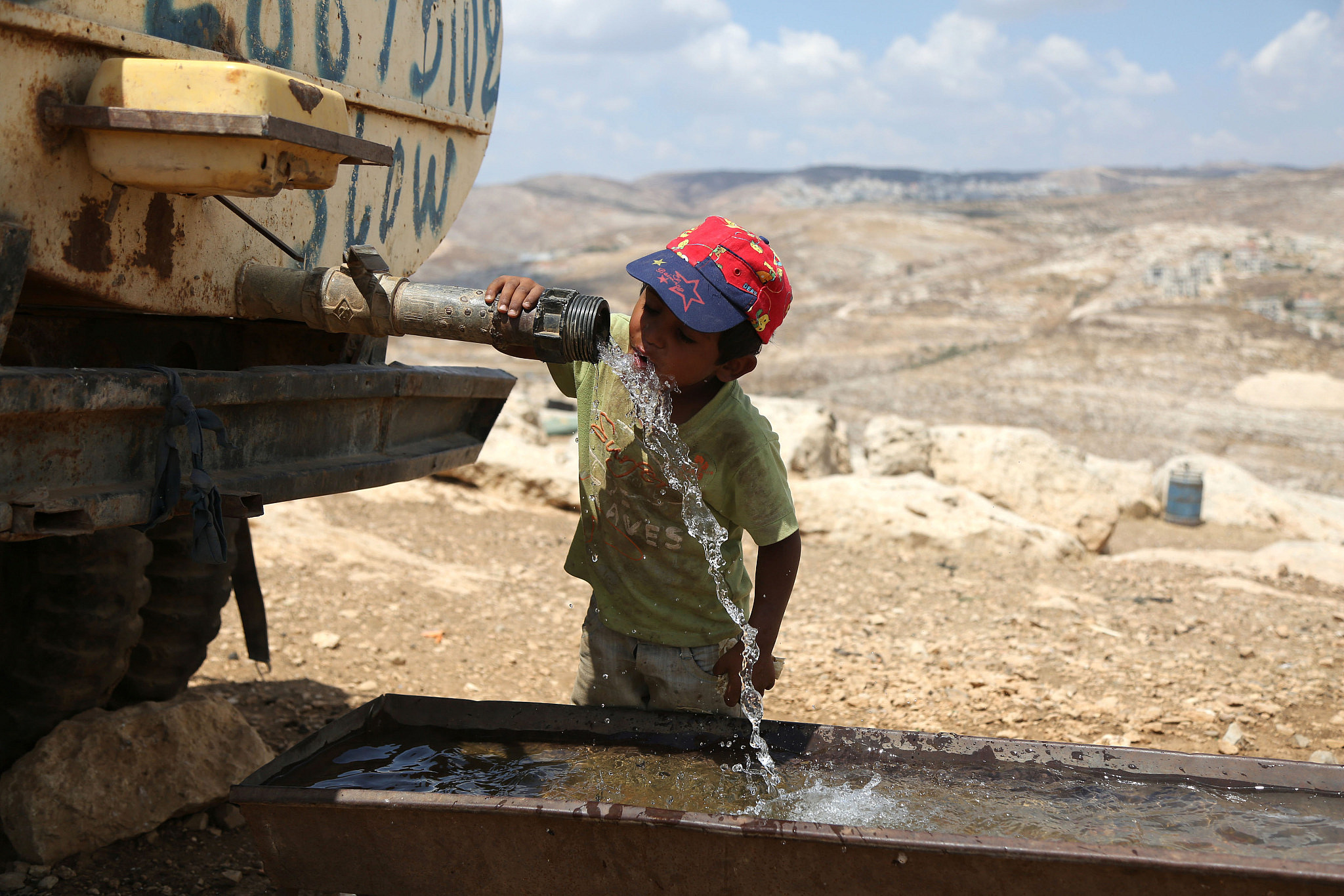 A Palestinian child drinks water near the rubble of his home which was demolished by Israeli bulldozers in the Palestinian village of Jaba, north of Jerusalem, August 31, 2015. (Flash90)