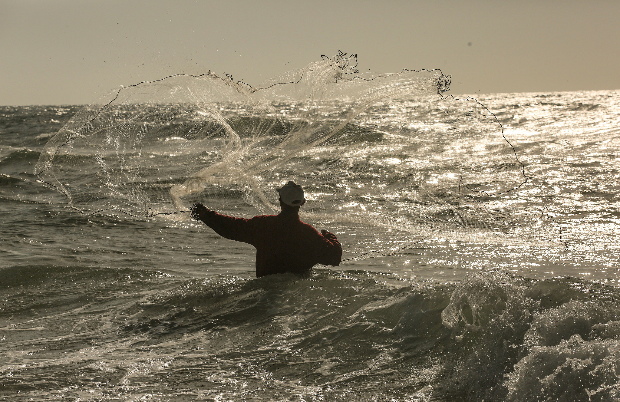 A Palestinian fisherman during a sunny day on the beach of Gaza City, June 5, 2020. (Mohammed Zaanoun/Activestills)