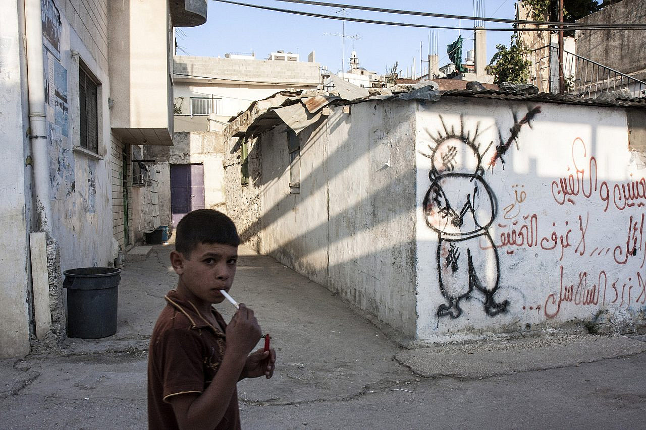 A Palestinian child passes in front of Handala graffiti in Al-Arroub refugee camp near Hebron in the occupied West Bank, November 3, 2008. (Anne Paq)