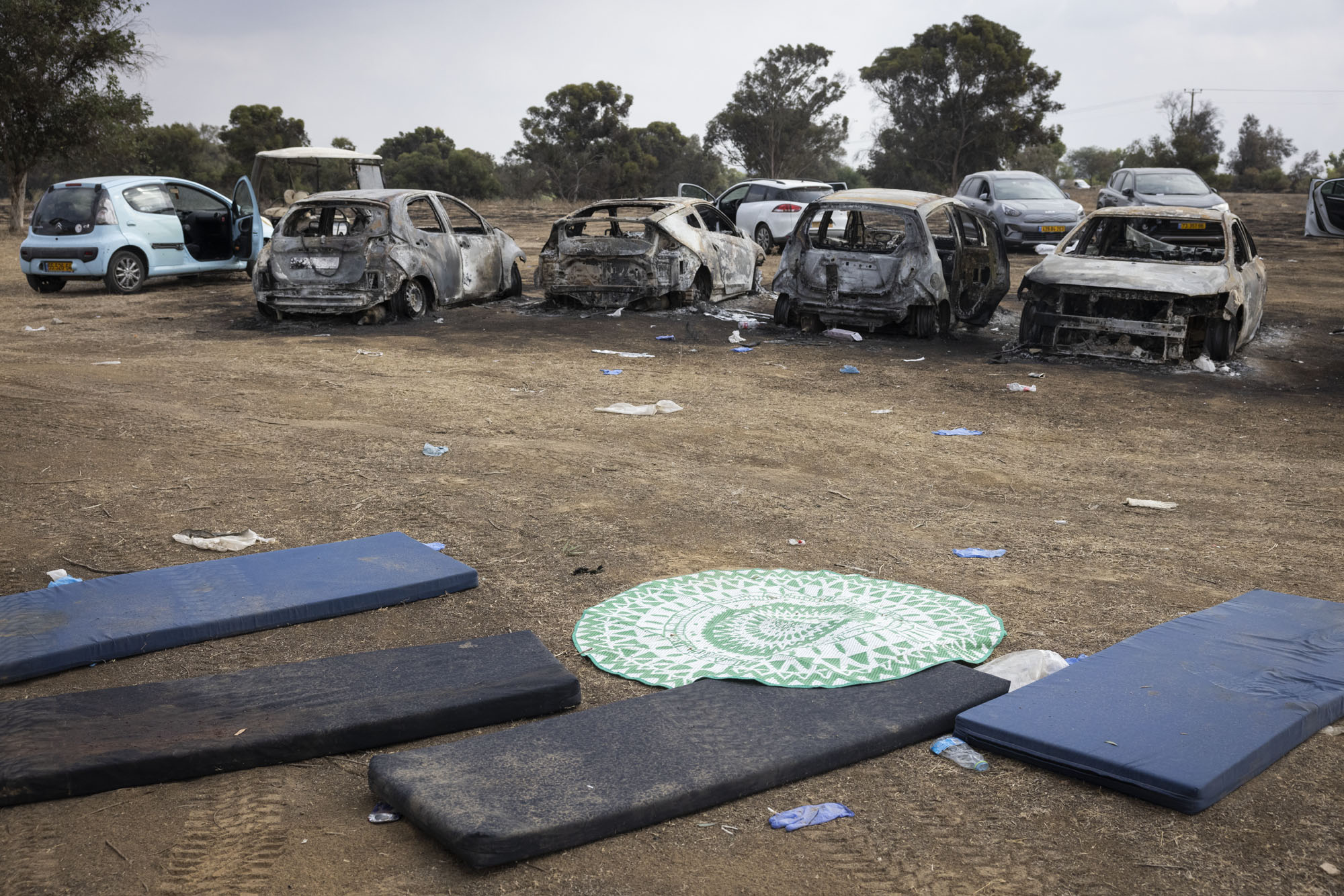 Burned-out cars and abandoned personal effects following a massacre at a music festival, Re'im, October 11, 2023. (Oren Ziv)