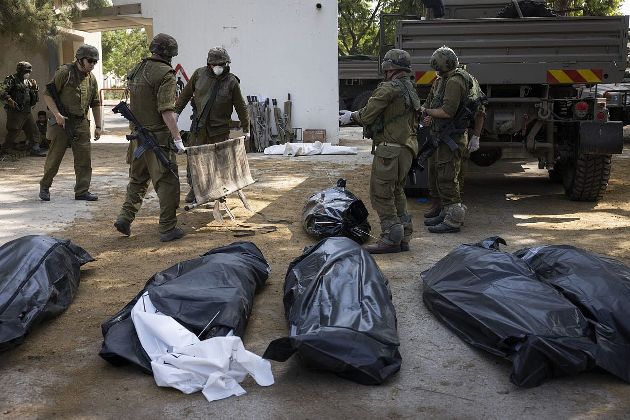 Israeli troops prepare to take away bodies from Kfar Aza after it was attacked by Hamas militants, October 10, 2023. (Oren Ziv)
