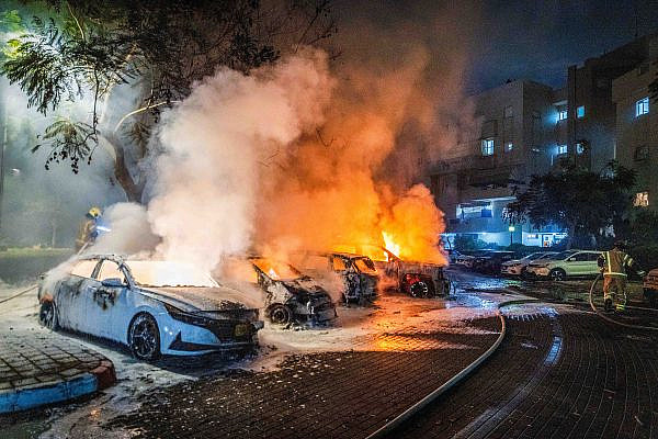 Firefighters try to put out burning cars at the scene where a rocket fired from Gaza landed in a residential area in Rishon LeZion, October 7, 2023. (Yossi Aloni/Flash90)