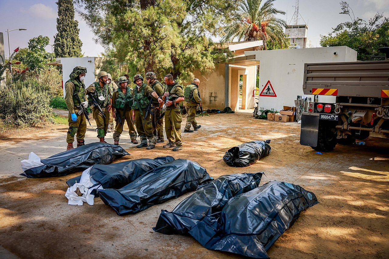 Israeli soldiers remove bodies of Israeli civilians in Kibbutz Kfar Aza, near the Israeli-Gaza fence, in southern Israel, October 10, 2023. (Chaim Goldberg/Flash90)