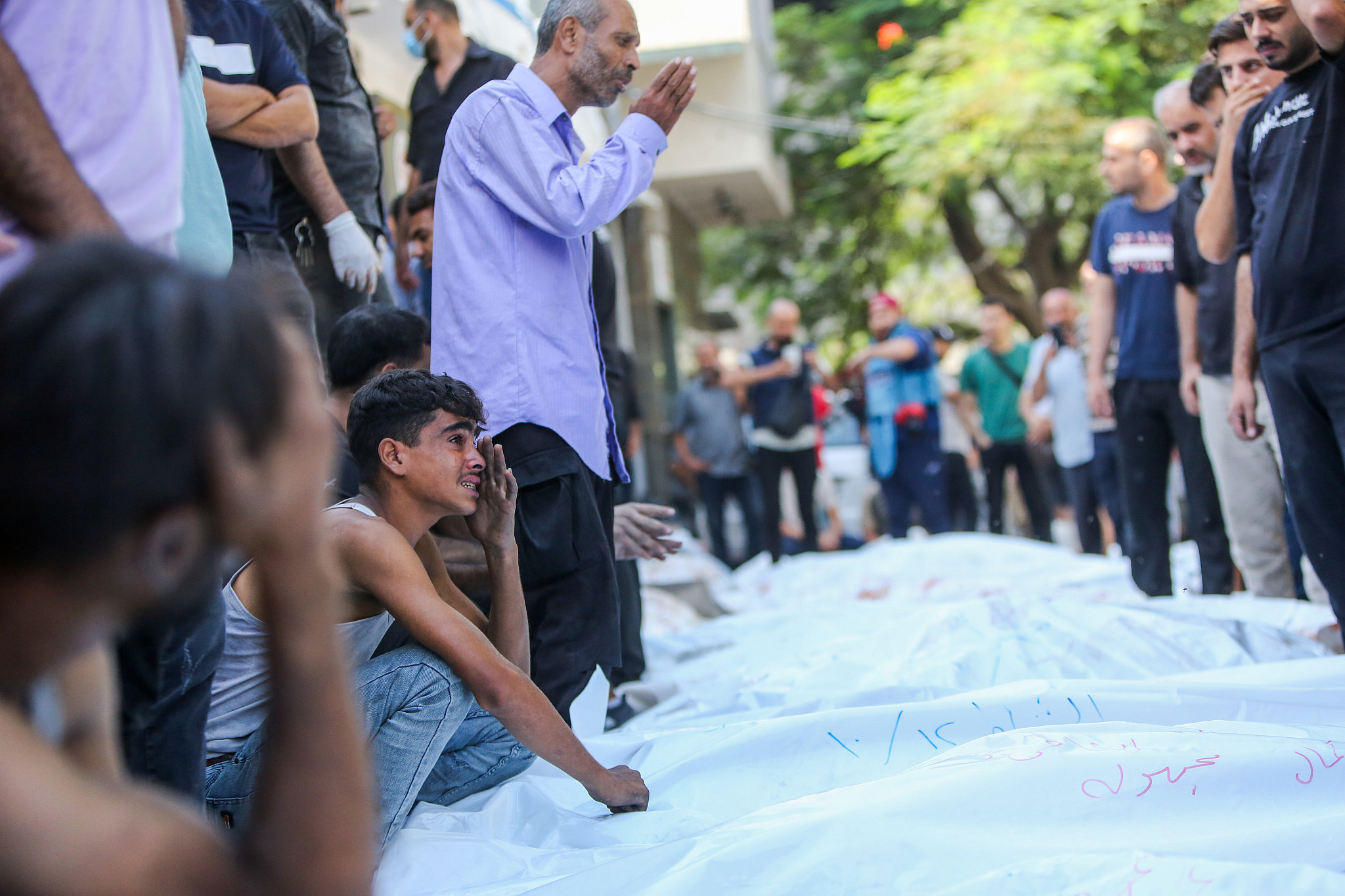 Palestinians mourn near bodies of people killed in Israeli air strikes, outside Al-Shifa Hospital in Gaza City, October 12, 2023. (Atia Mohammed/Flash90)