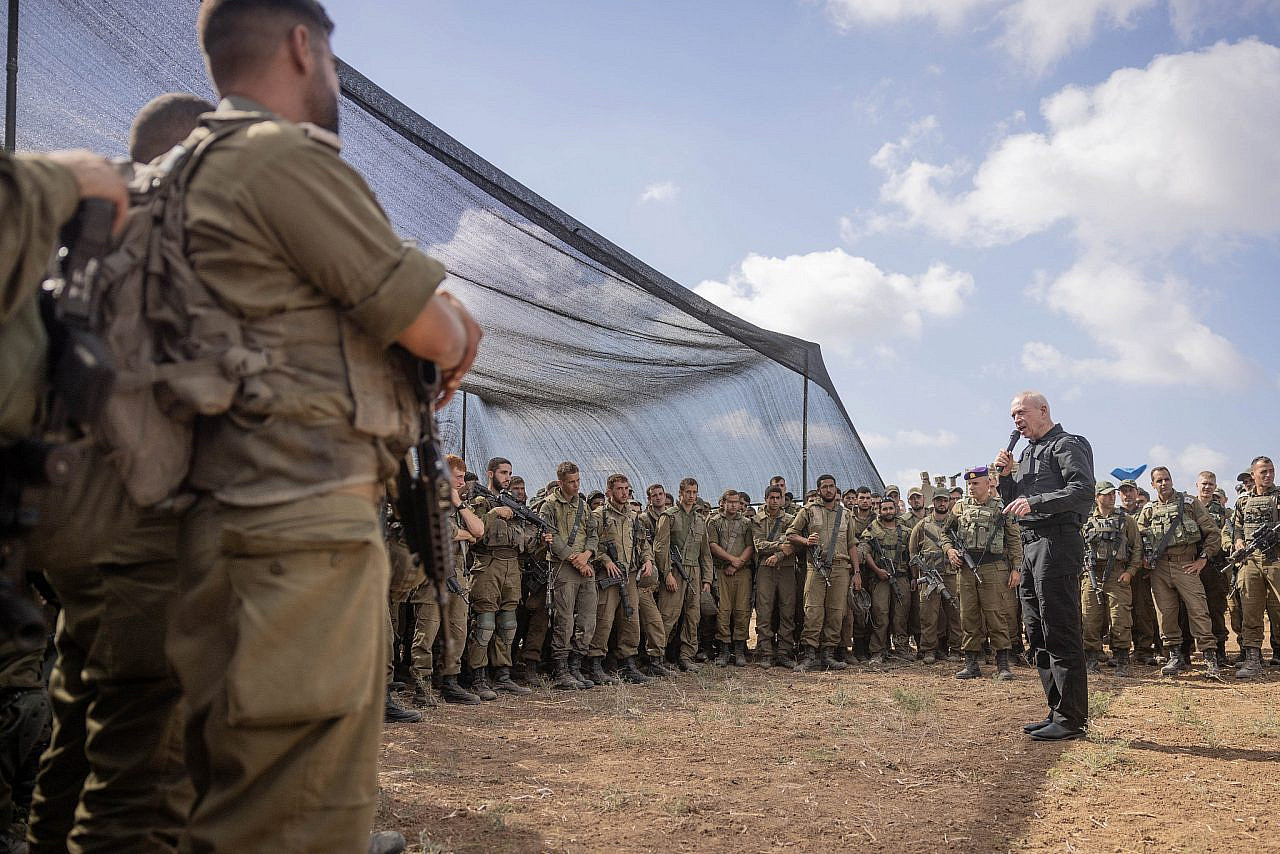 Defence Minister Yoav Gallant speaks with Israeli soldiers at a staging area not far from the Gaza fence, October 19, 2023. (Chaim Goldberg/Flash90)