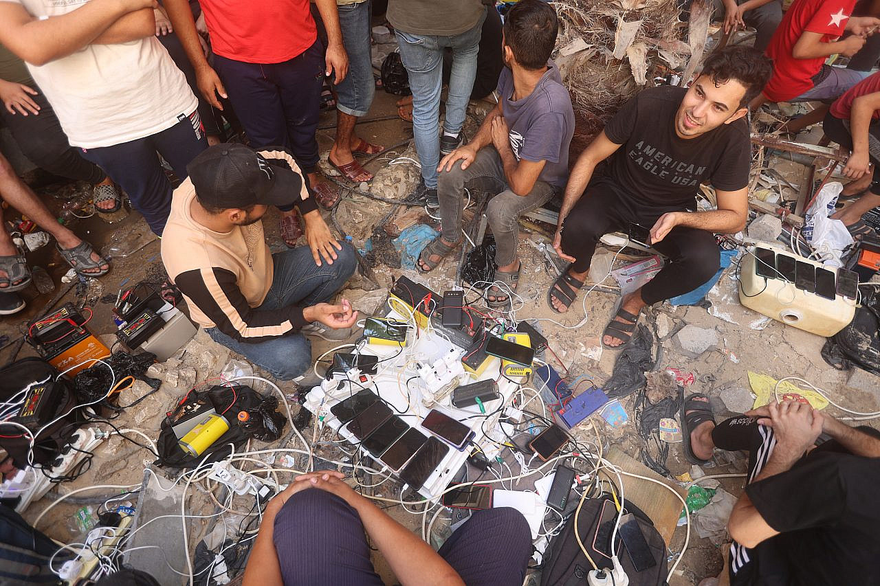 Palestinians charge their phones outside a hospital in Khan Younis, in the southern Gaza Strip, October 23, 2023. (Atia Mohammed/Flash90)