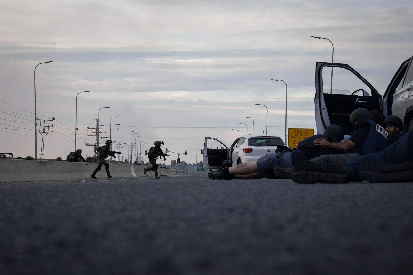 A group of journalists takes cover from Hamas gunfire as Israeli forces arrive, between Sderot and Netivot, October 7, 2023. (Oren Ziv)
