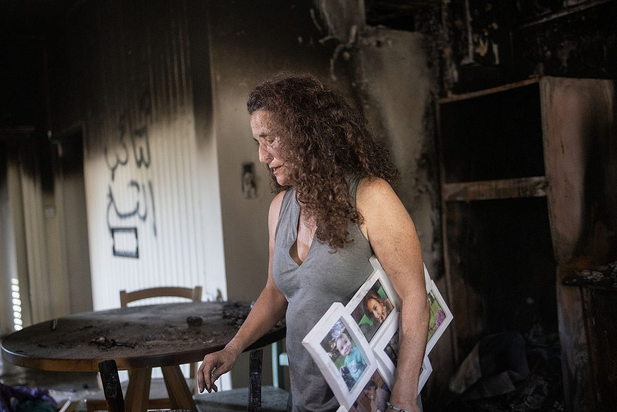 Hadas Calderon holds photos of her children in the house from which they were kidnapped by Hamas militants, October 30, 2023. (Oren Ziv)