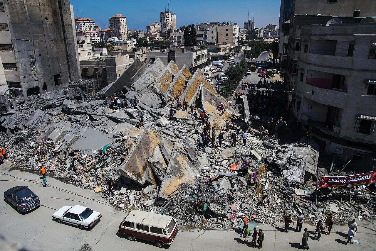 Palestinians gather around the remains of a tower building housing offices which witnesses said was destroyed by an Israeli air strike in Gaza City, August 26, 2014. (Emad Nassar/Flash90)