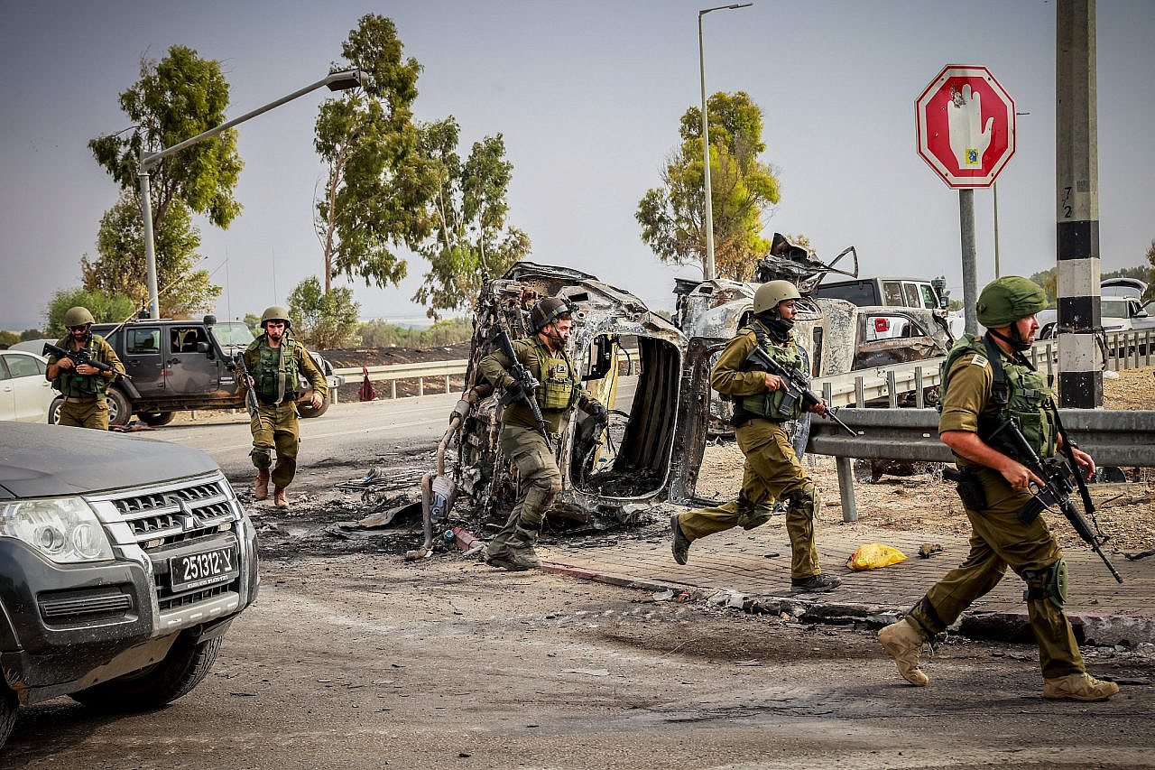 Les forces de sécurité israéliennes sont vues à côté de voitures incendiées près de l’entrée du kibboutz Beeri, dans le sud d’Israël, le 9 octobre 2023. (Yossi Zamir/Flash90)