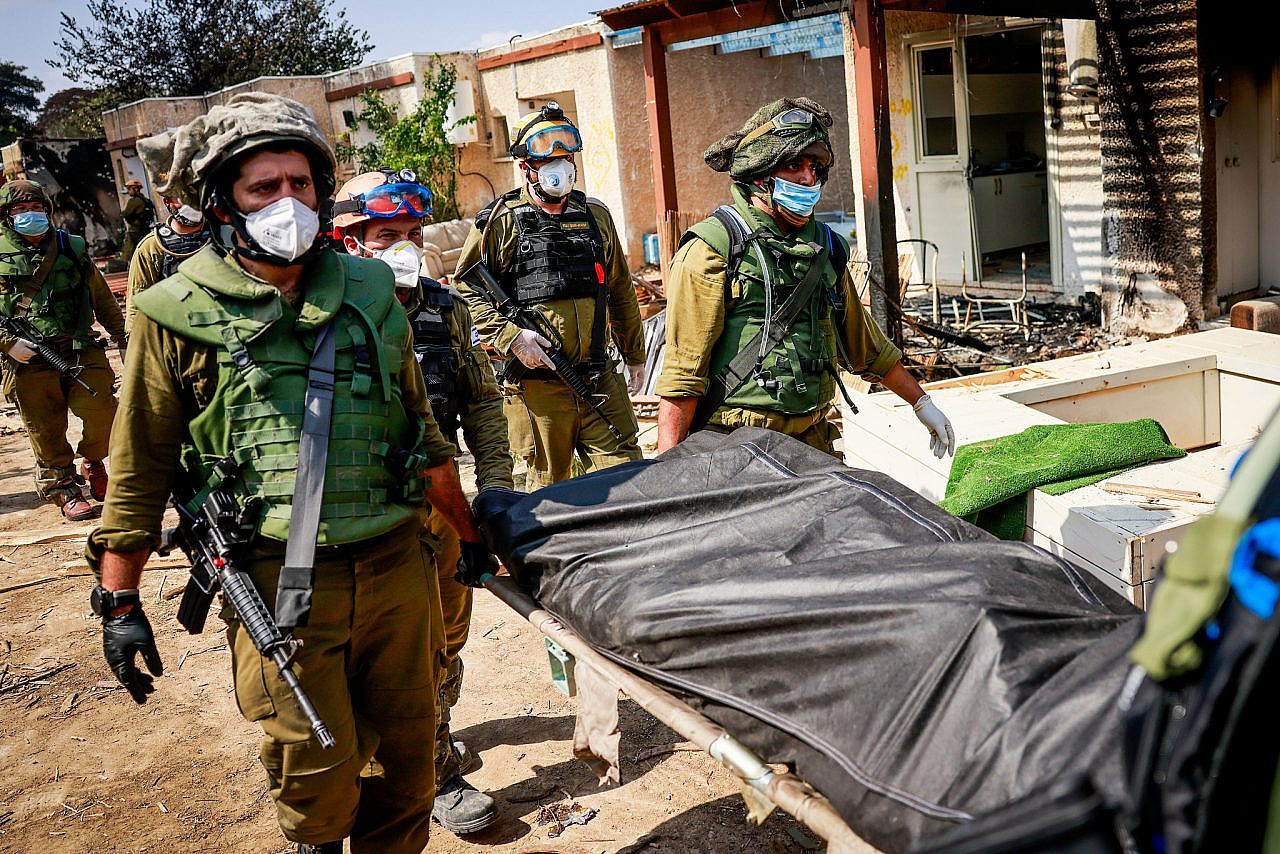 Israeli soldiers remove bodies of Israeli civilians killed by Hamas militants in Kibbutz Kfar Aza, southern Israel, October 10, 2023. (Chaim Goldberg/Flash90)