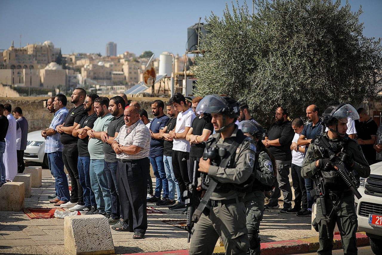 Israeli police watch on as Palestinians pray in the streets of the East Jerusalem neighborhood of Ras El Amud, November 3, 2023. (Jamal Awad/FLASH90)