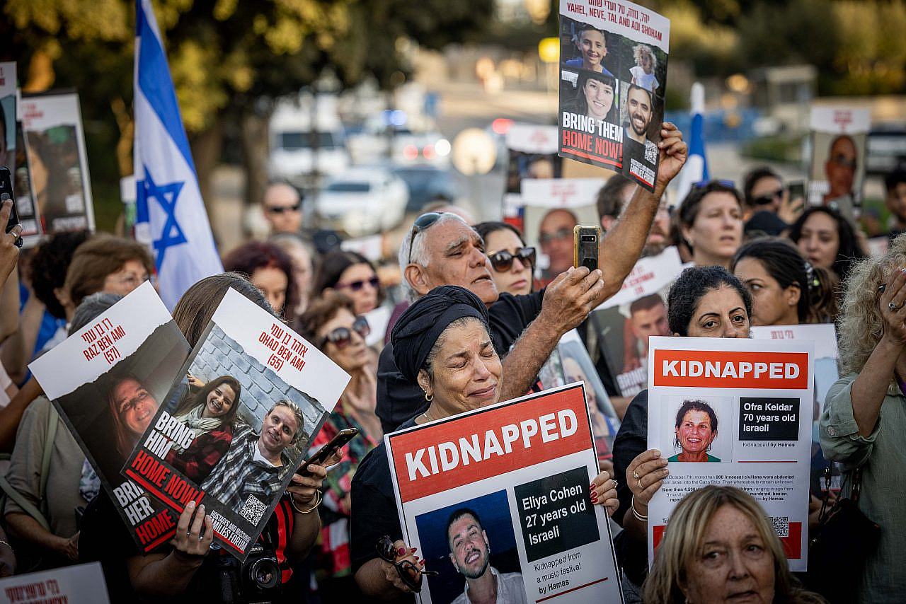 Israelis hold photographs of abducted and missing family members during a protest outside the Knesset, Jerusalem, November 6, 2023. (Yonatan Sindel/Flash90)