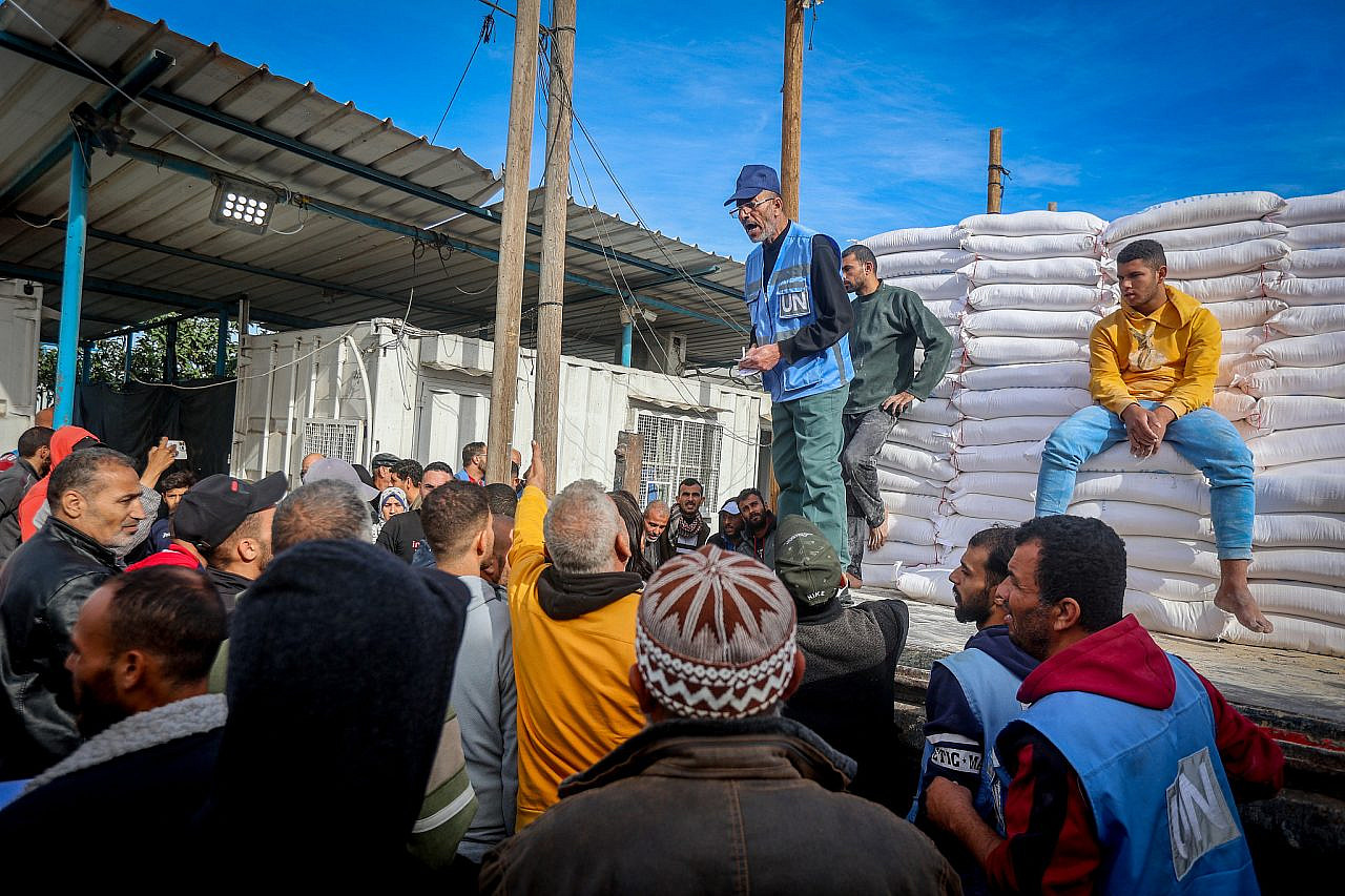 Palestinians receive bags with flour at the United Nations Relief and Works Agency (UNWRA) in Khan Younis, southern Gaza Strip, November 22, 2023. (Atia Mohammed/ Flash90)