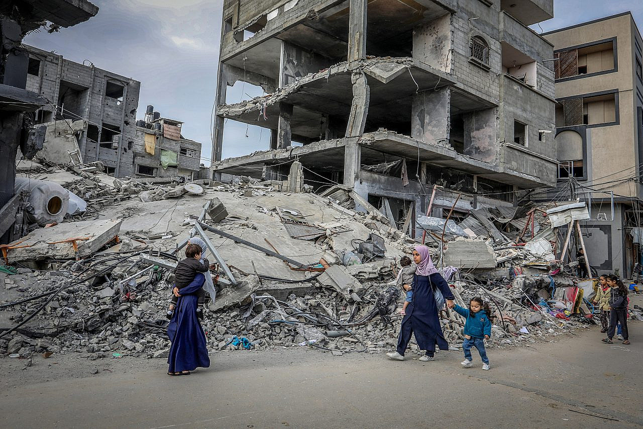 Palestinians walk next to the rubble of buildings destroyed by Israeli airstrikes in Rafah, southern Gaza Strip, November 27, 2023. (Abed Rahim Khatib/Flash90)