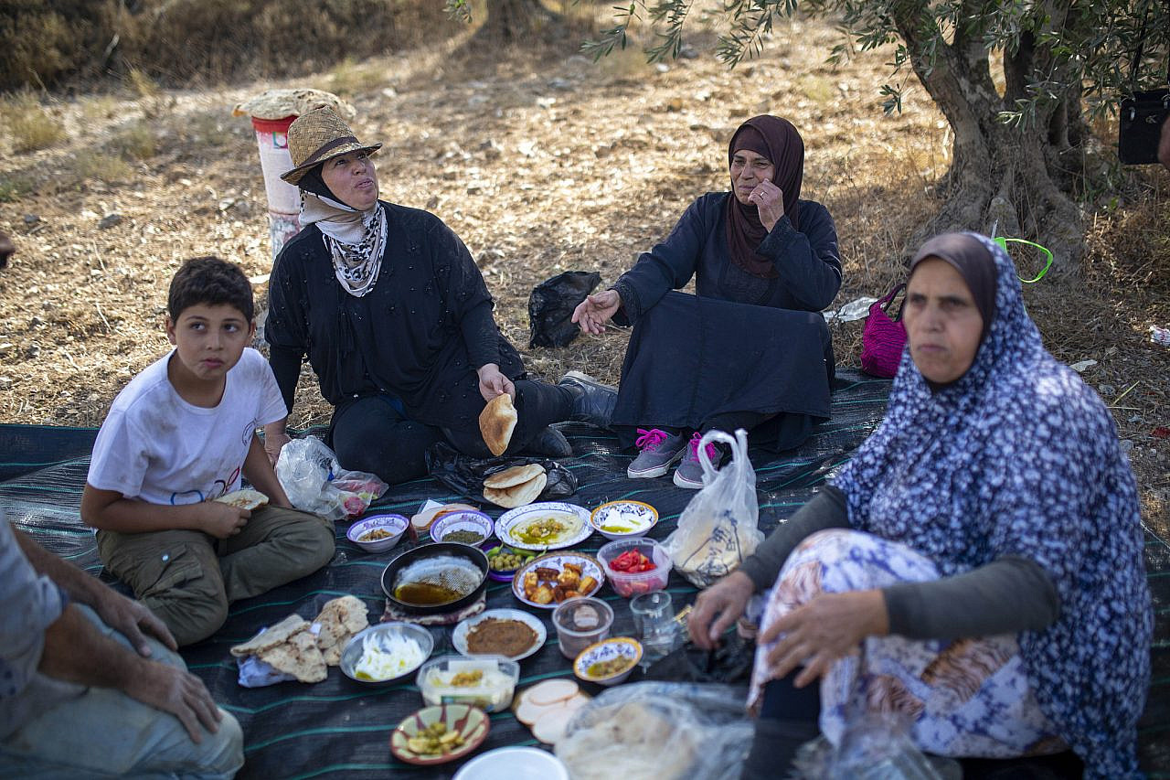 Doha Asous, known as Um Musa, sits with her relatives for lunch during the olive harvest in Burin, occupied West Bank, October 15, 2022. (Anne Paq/Activestills)