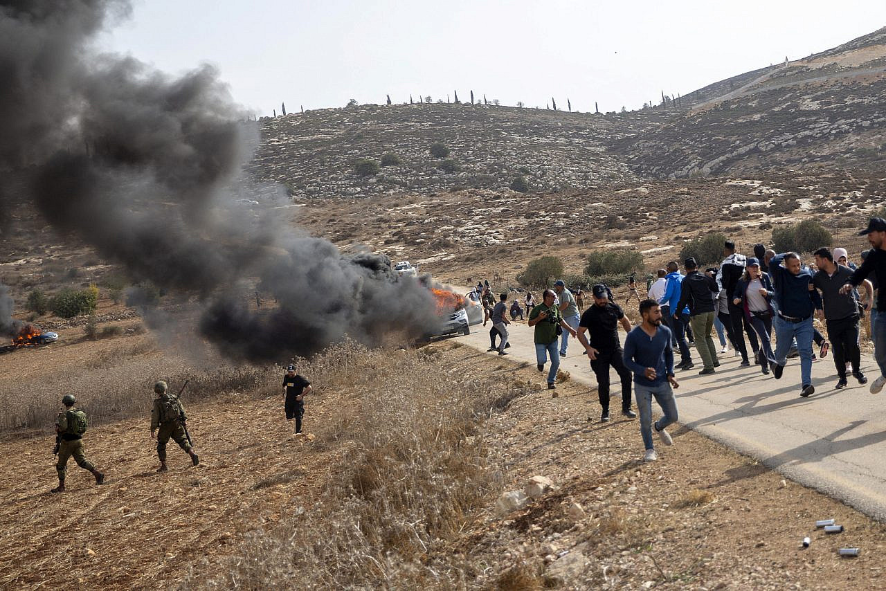 Israeli settlers attack Palestinian farmers and activists to prevent them from picking their olive trees near the Israeli outpost of the Shilo settlement, on lands belonging to the Palestinian town of Turmus Ayya, occupied West Bank, October 25, 2022. (Anne Paq/Activestills)