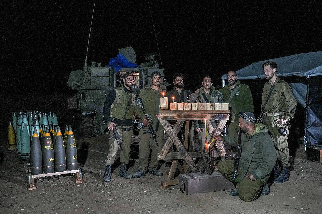 Israeli soldiers light candles on the first night of the Jewish holiday of Hanukkah at a staging area near the Gaza fence, southern Israel, December 7, 2023. (Flash90)