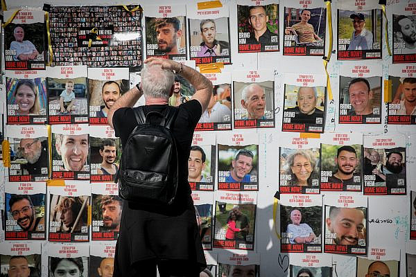 People walk by photographs of Israelis held hostage in Gaza at "Hostage Square" in Tel Aviv, December 12, 2023. (Miriam Alster/FLASH90)