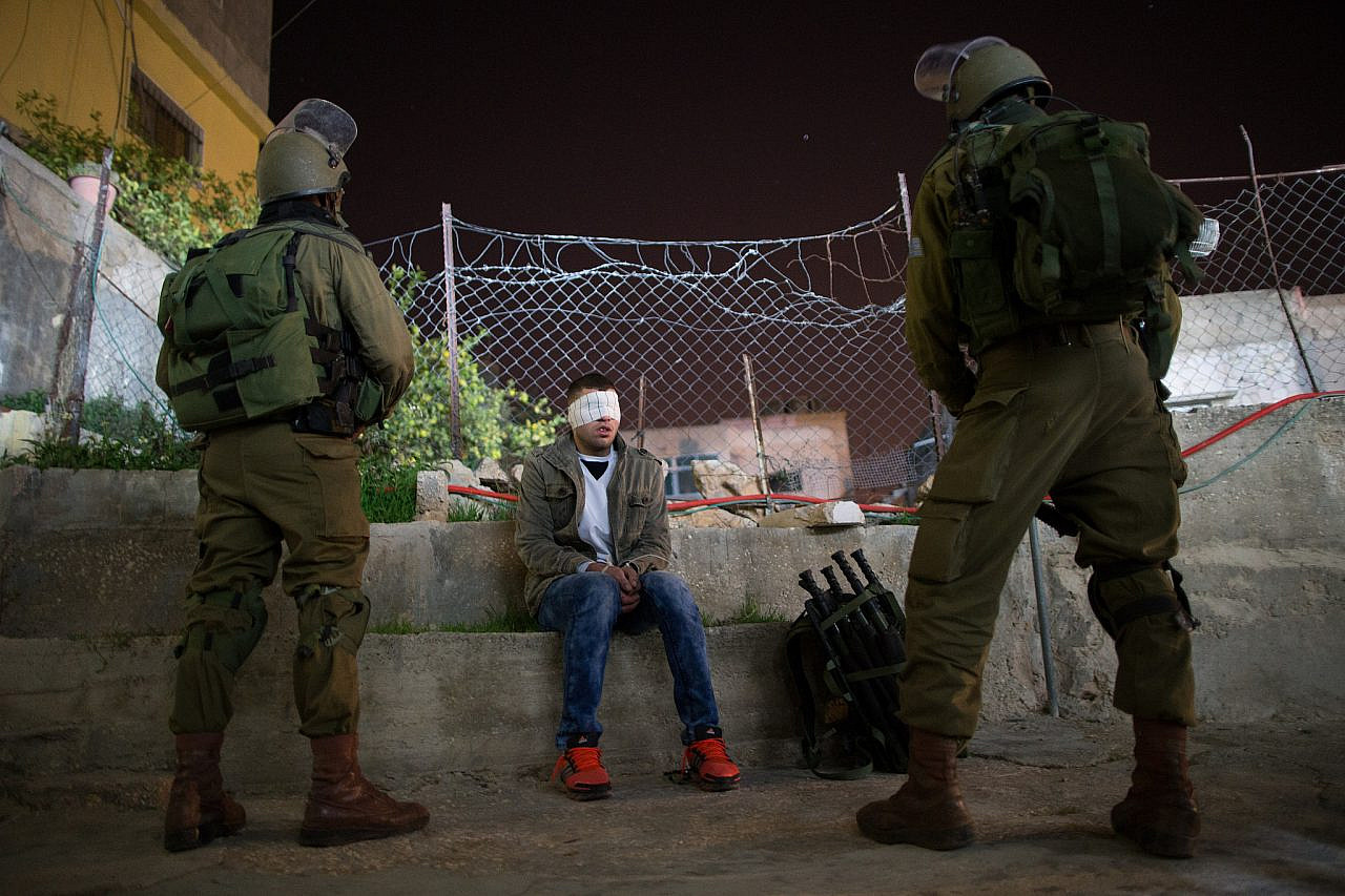 Israeli soldiers from the Nachshon Battalion soldiers watch over a Palestinian detainee during an arrest operation in the Deheisha Refugee Camp, near the West Bank city of Bethlehem, overnight on December 8, 2015. (Photo by Nati Shohat/Flash90)