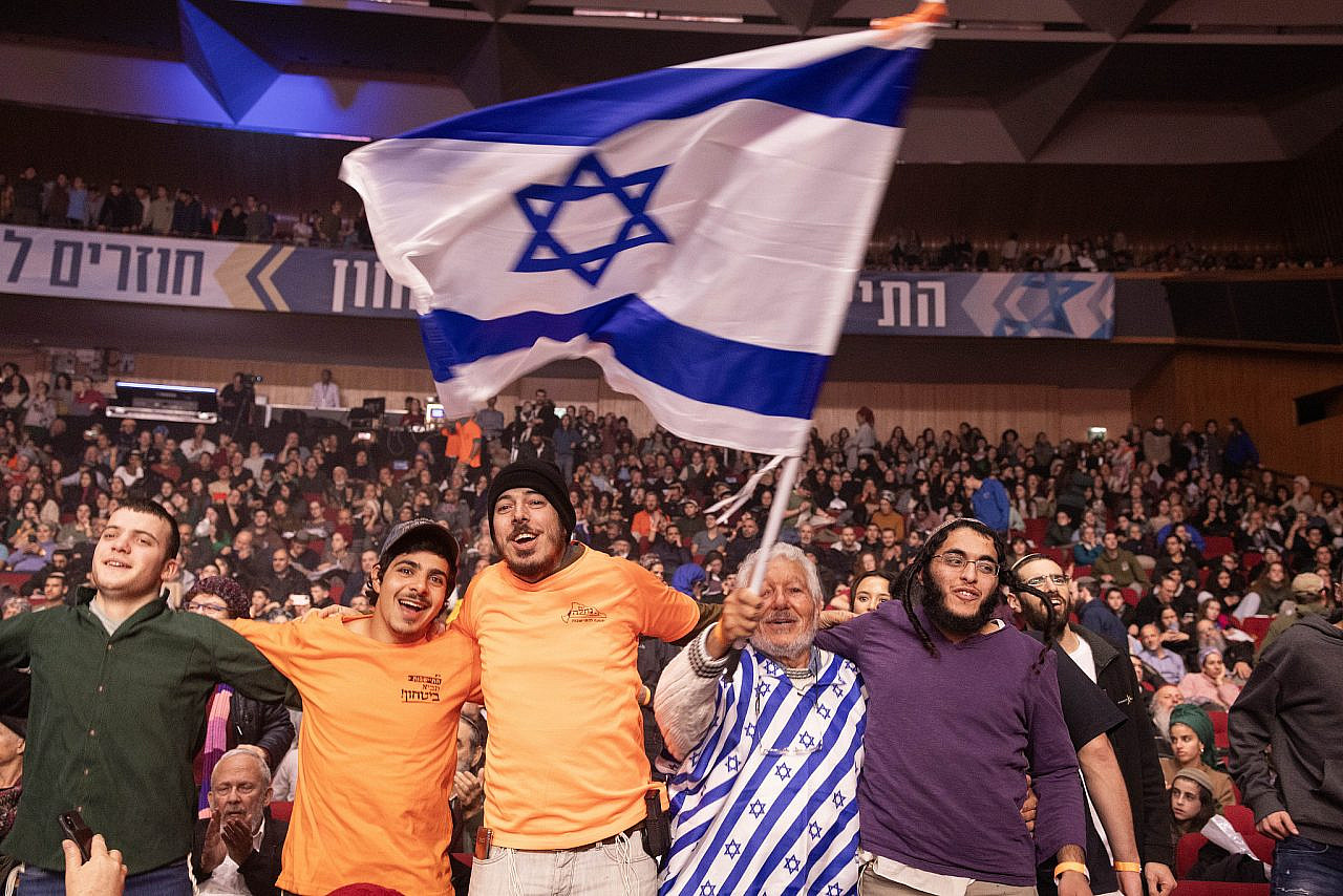 Israelis dance and wave flags at the "Conference for Israel's Victory" in Jerusalem, January 28, 2024. (Oren Ziv)