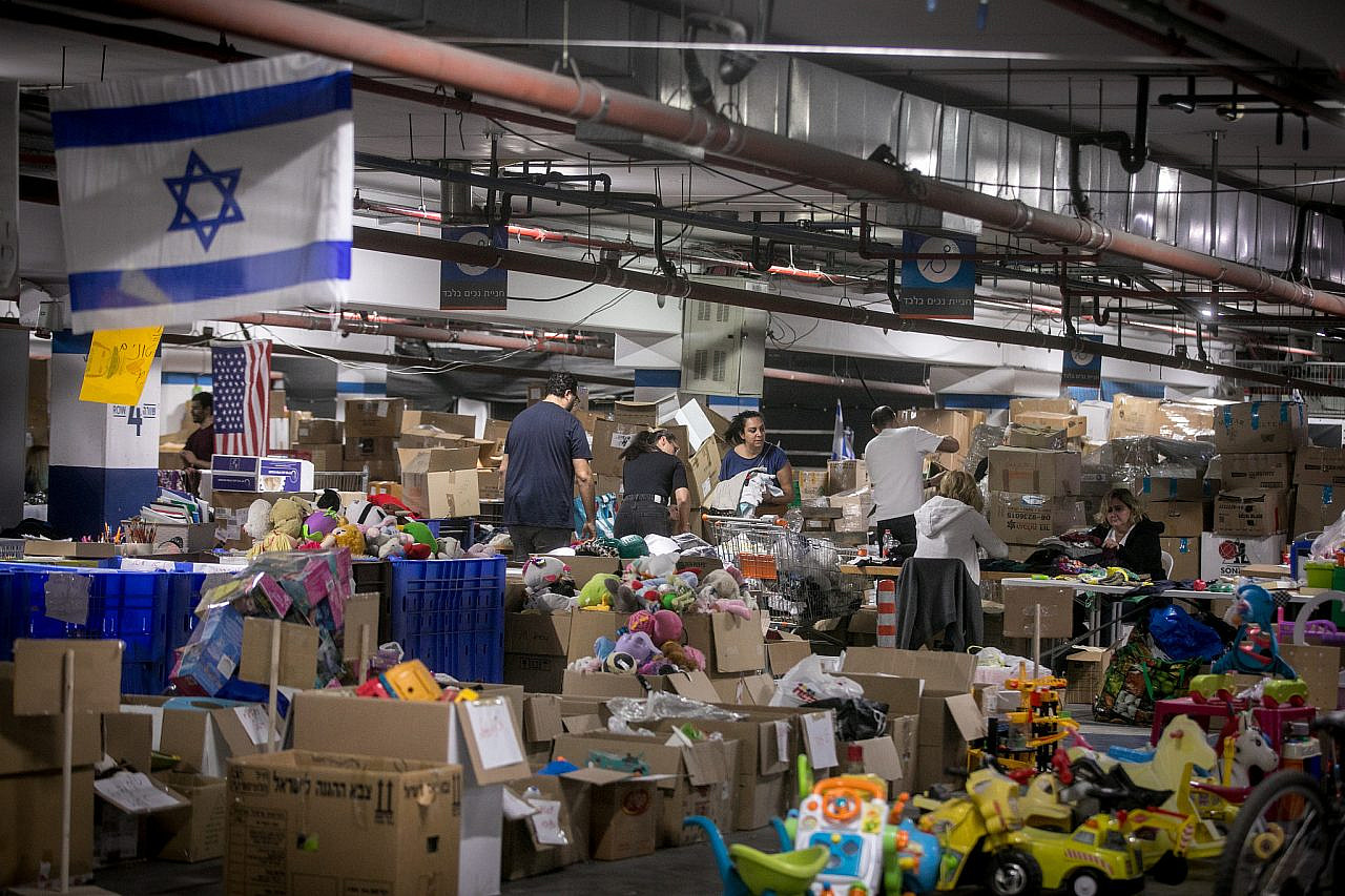 Volunteers pack donations of clothes, food, toys, and other necessities for people who were evacuated from southern and northern Israel in Tel Aviv, December 28, 2023. (Miriam Alster/Flash90)