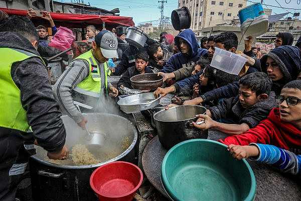 Palestinians wait for a hot meal prepared by volunteers in Rafah, southern Gaza Strip, January 26, 2024. (Abed Rahim Khatib/Flash90)