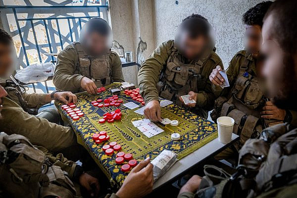 Israeli soldiers play cards inside a building in Al-Shati refugee camp, northern Gaza Strip, November 16, 2023. (Yonatan Sindel/Flash90)