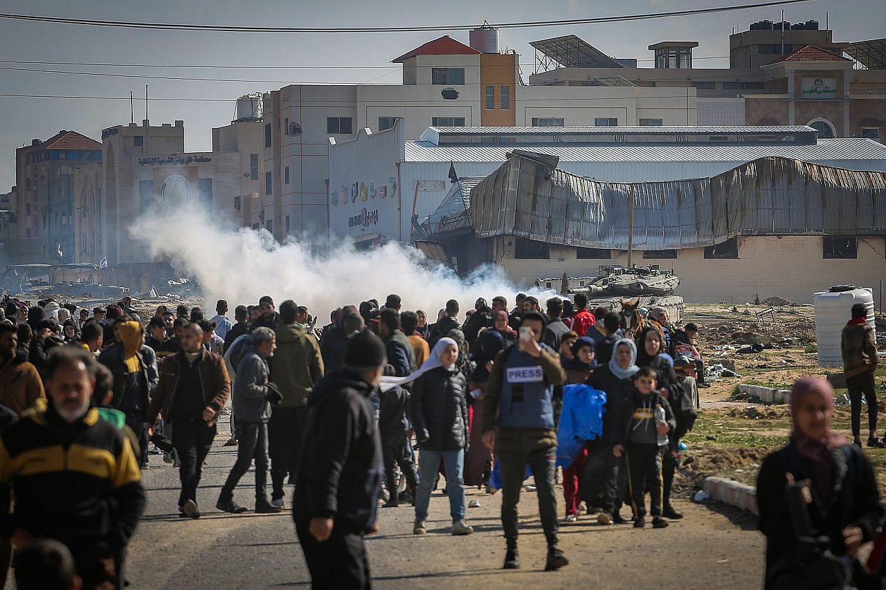 Israeli forces watch on as Palestinians flee Khan Younis in the southern Gaza Strip, January 26, 2024. (Atia Mohammed/Flash90)