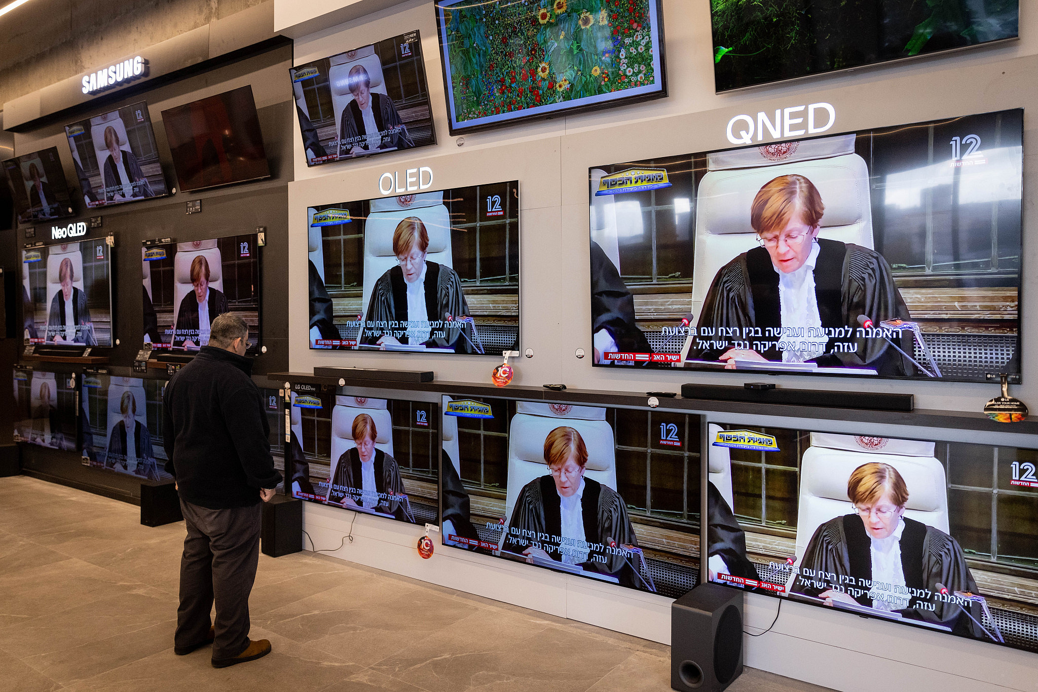 A man looks at television screens broadcasting a court hearing from the International Court of Justice in the lawsuit of South Africa against Israel, at a shop in Jerusalem, January 26, 2024. (Chaim Goldberg/Flash90)